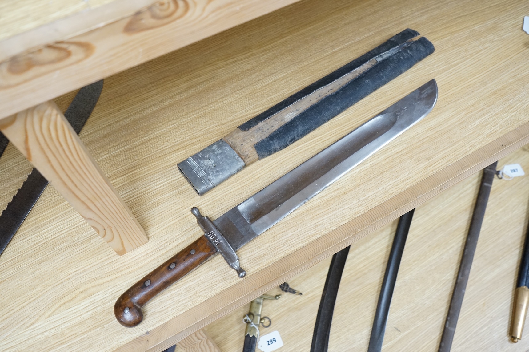 A 19th century Austrian military fascine knife, regulation iron crosspiece, two piece riveted wooden grips, in its wooden scabbard with iron mounts, leather covering loose